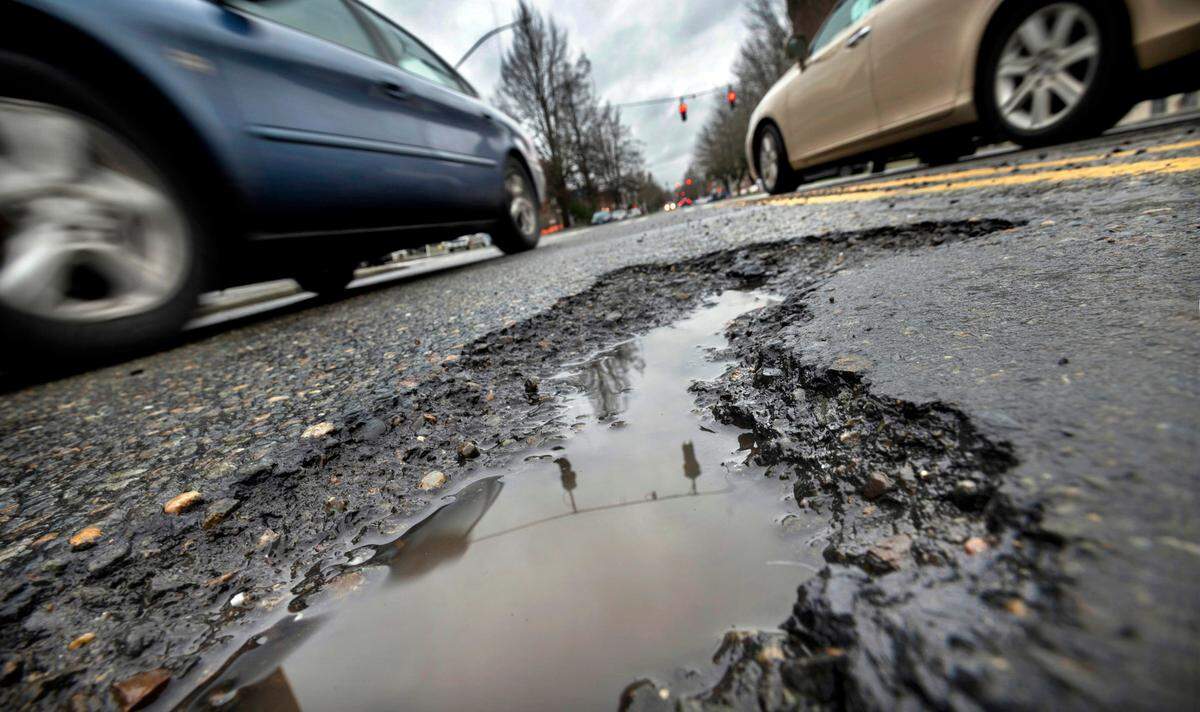 Traffic rolls past deep pothole on South Yakima Avenue in Tacoma, Washington, on Wednesday, Jan. 5, 2022.
