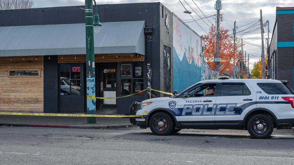 Tacoma police remained on the scene Sunday afternoon of an early-morning shooting that killed two and wounded three at a business on 6th Avenue.