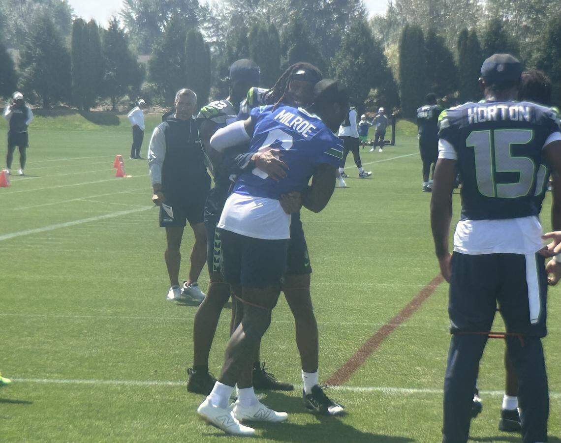 Rookie wide receiver Tyrone Broden (left center) from Arkansas hugs rookie quarterback Jalen Milroe from Alabama as they joke before the start of the 12th practice of Seattle Seahawks NFL training camp at the Virginia Mason Athletic Center in Renton Aug. 5, 2025.