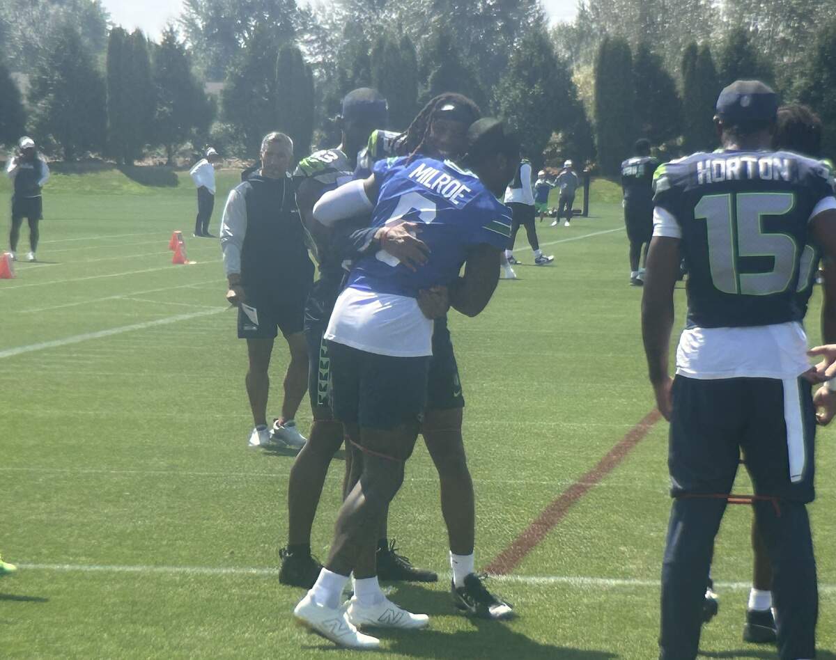 Rookie wide receiver Tyrone Broden (left center) from Arkansas hugs rookie quarterback Jalen Milroe from Alabama as they joke before the start of the 12th practice of Seattle Seahawks NFL training camp at the Virginia Mason Athletic Center in Renton Aug. 5, 2025.