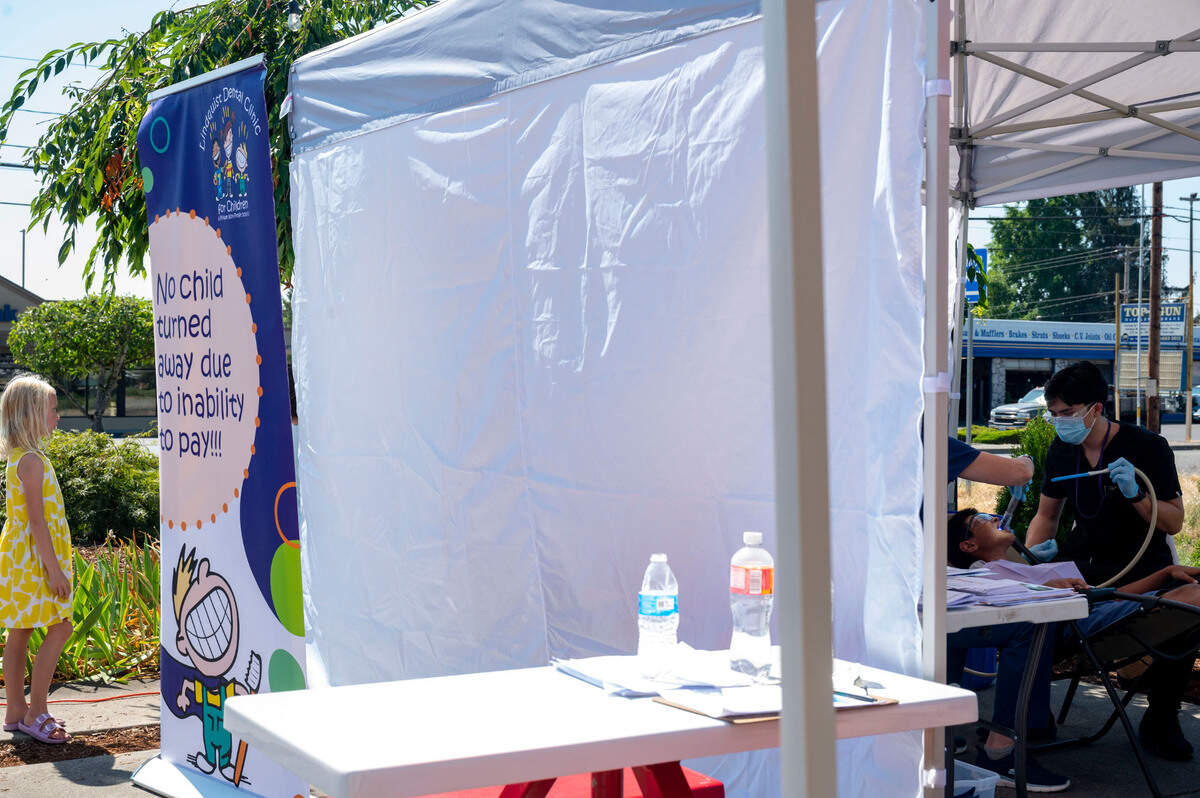 A young child gets dental care from Lindquist Dental Clinic for Children staff outside the Sumner Community Food Bank during a community event on Thursday, Aug. 25, 2022, in Sumner, Wash.