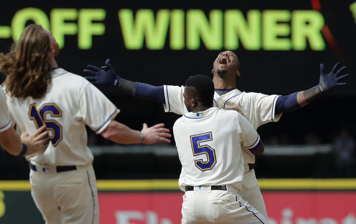 Seattle Mariners' Jean Segura, right, celebrates with Guillermo Heredia (5) and Ben Gamel, left, after hitting a walkoff RBI-single to score Dee Gordon and give them a victory over the Detroit Tigers in the 11th inning of a baseball game Sunday, May 20, 2018, in Seattle. (AP Photo/Ted S. Warren)