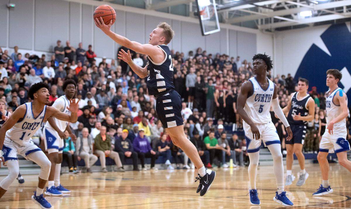 Olympia’s Parker Gerrits slips to the basket between Curtis defenders Cinque Maxwell and Zoom Dialo (5) during Saturday night’s 4A SPSL boys basketball tournament championship game at Tacoma Community College in Tacoma, Washington, on Feb. 4, 2023.