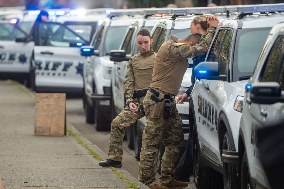 Pierce County Sheriff’s Department personnel stand alongside their cars as they prepare for the procession to begin for Deputy Dom Calata’s celebration of life on Friday, March 25, 2022, in Puyallup.