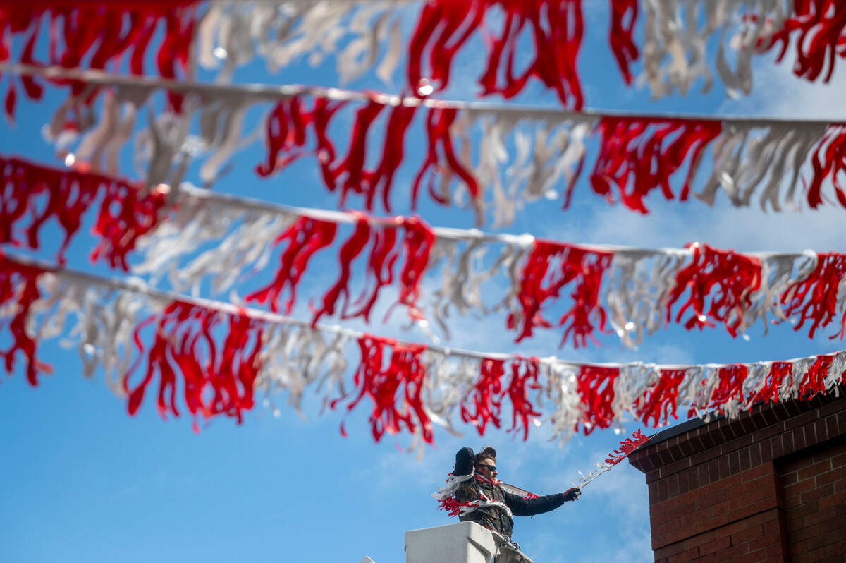 A gust of wind nearly blows the hat off of Nick Fitzinger’s head as he puts up streamers on a Safeway on the 2600 block North Pearl Street in Tacoma, Wash., on Monday, April 4, 2022. High winds and intermittent rain storms caused power outages across Pierce County on Monday.