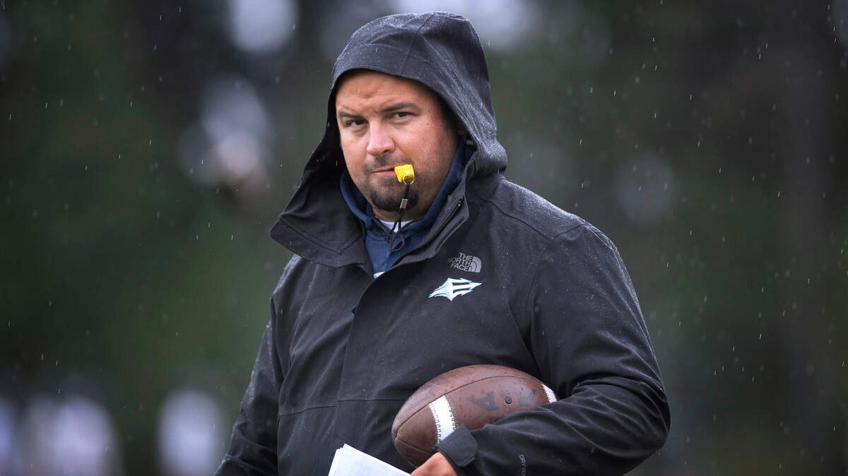 Gig Harbor head coach Darrin Reeves weathers a rain shower as he directs the Tides during preseason football practice at Gig Harbor High School in Gig Harbor, Washington, on Friday, Aug. 23, 2024.