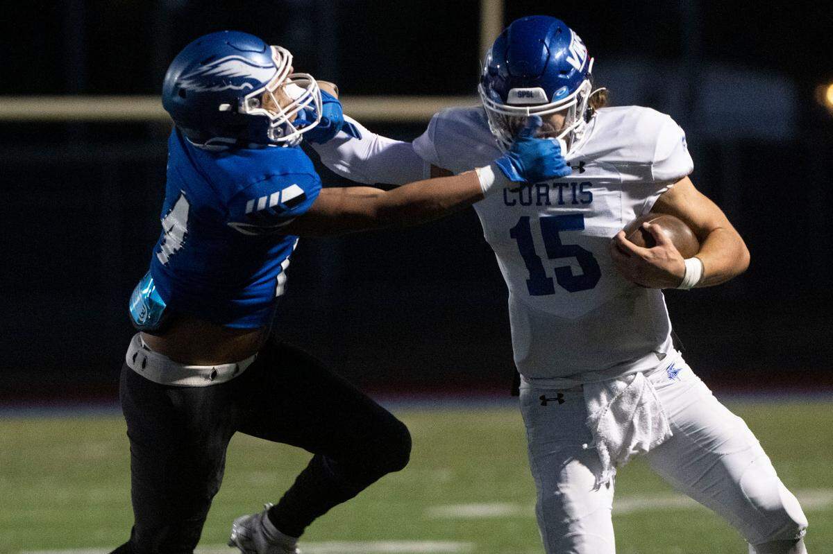 Curtis quarterback Rocco Koch stiff arms Federal Way’s Keshawn Pham-Roberts on a run up the sideline during the first quarter of a Week 10 4A playoff game on Saturday, Nov. 5, 2022, at Federal Way Memorial Field in Federal Way, Wash.