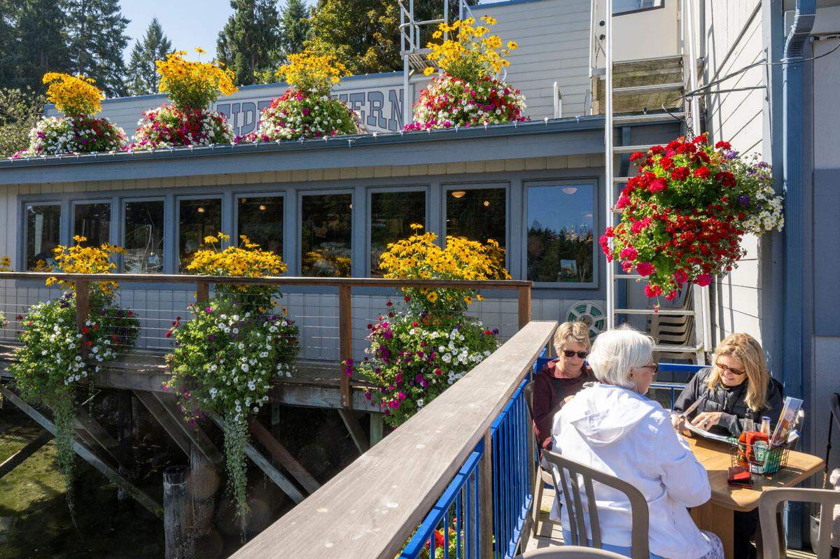 Flowers accent the deck of Tides Tavern as a group of women enjoy the sunshine during lunch on Friday, Sept. 8, 2023, in Gig Harbor, Wash.