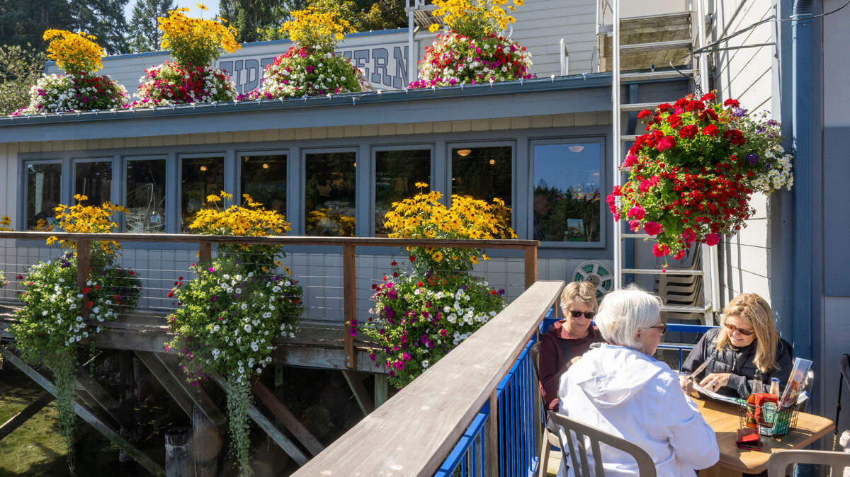 Flowers accent the deck of Tides Tavern as a group of women enjoy the sunshine during lunch on Friday, Sept. 8, 2023, in Gig Harbor, Wash.