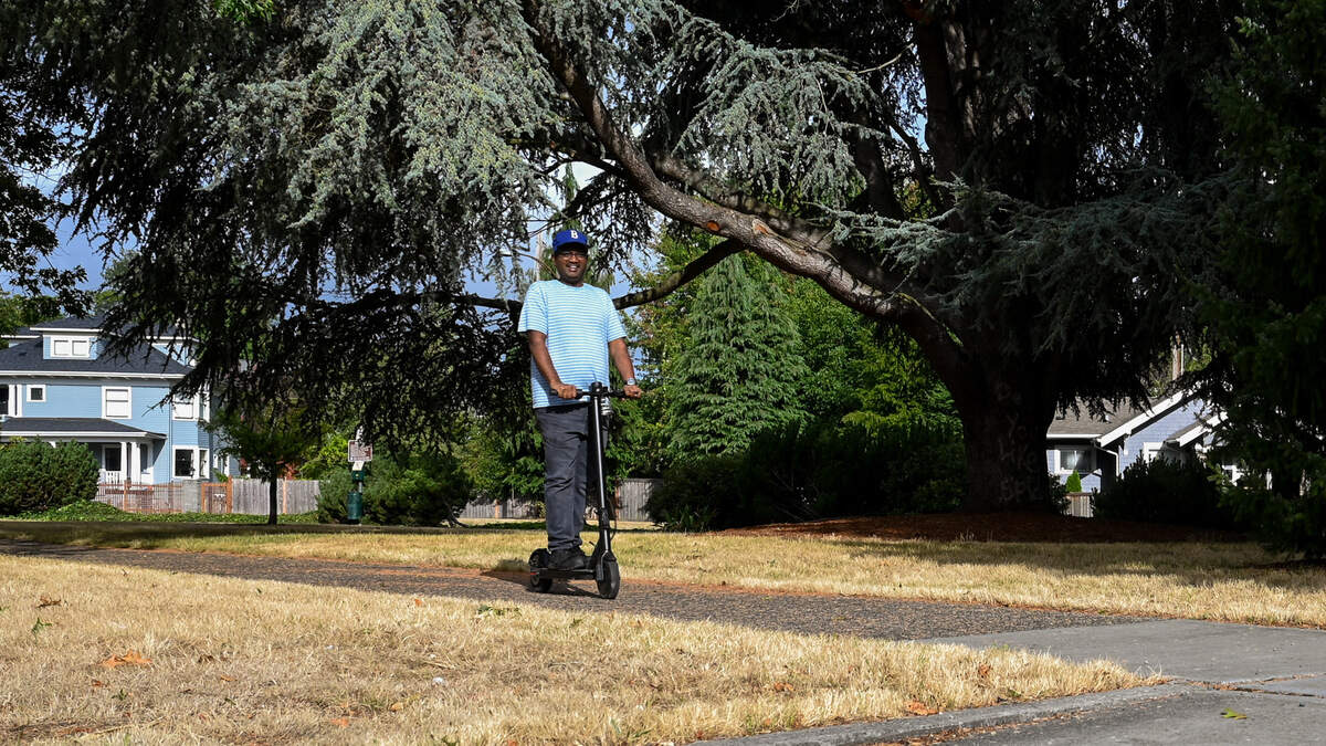 A Tacoma resident flashes a smile while riding his scooter through the newly named Dr. W. Joye Hardiman Park on Wednesday, Aug. 21, 2024 in Tacoma, WA.