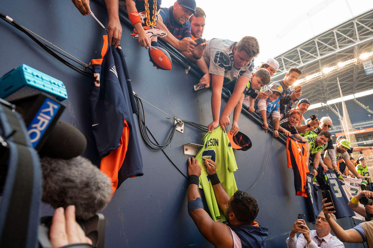 Denver Broncos quarterback Russell Wilson (3) signs his former Seattle Seahawks jersey for a fan as he walks off the field after warmups prior to the start of an NFL game on Monday, Sept. 12, 2022, at Lumen Field in Seattle.