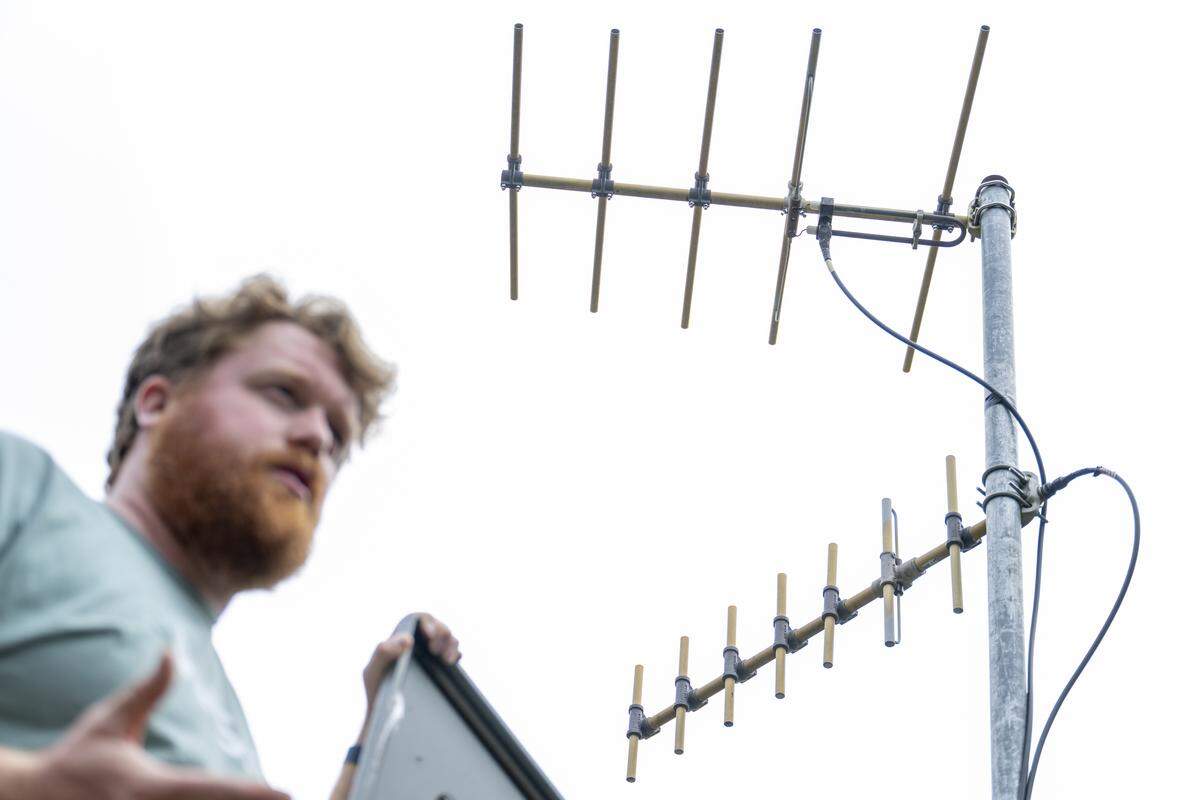 An antenna mast roughly 12 feet tall hangs above Doug Gibbons, a field technician and seismology lab coordinator for the Pacific Northwest Seismic Network, as he stands by one of the organization’s seismic stations on a farm in Graham on Thursday, Sept. 11, 2025.