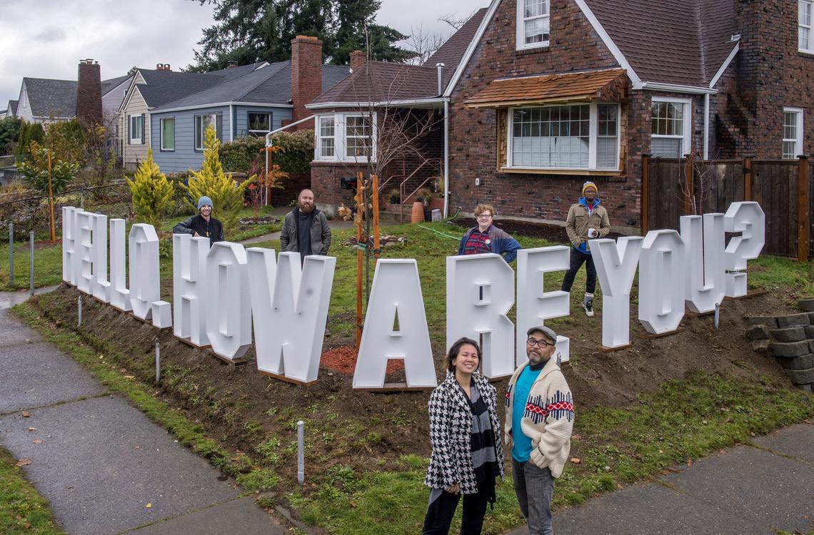 Anida Yoeu Ali (foreground, left) and Masahiro Sugano stand in front of their Hilltop home with a new art installation, “Hello. How are you?”, Nov. 23, 2018. Behind are four of the five who also worked on the piece, Danny Connelly (left), Vince Rehm, Stella Kemper and Joshua Sembly.