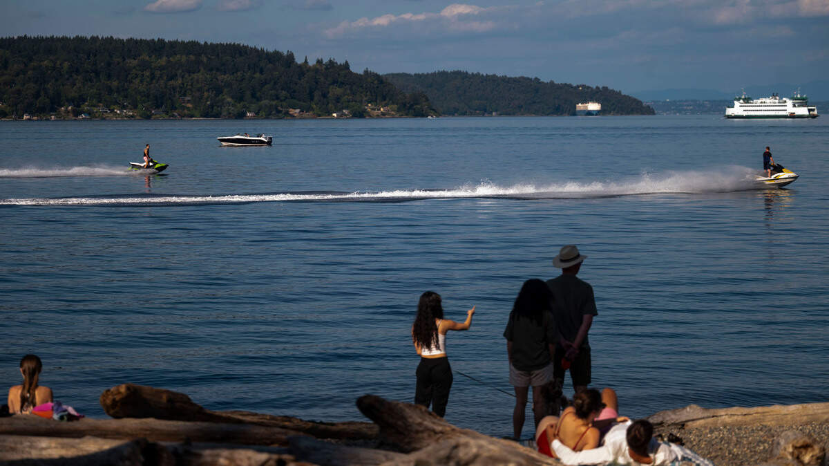 People watch as jet skiers speed past Owen Beach on Wednesday, Aug. 14, 2024, in Tacoma.