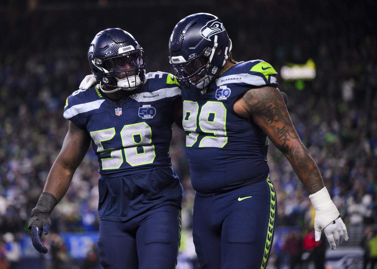 Seattle Seahawks linebacker Derick Hall (58) and defensive end Leonard Williams (99) hugs after a 4th down stop against Los Angeles Rams quarterback Matthew Stafford (9) and the Los Angeles Rams during the fourth quarter of the NFC Championship game at Lumen Field, on Sunday, Jan. 25, 2026, in Seattle.