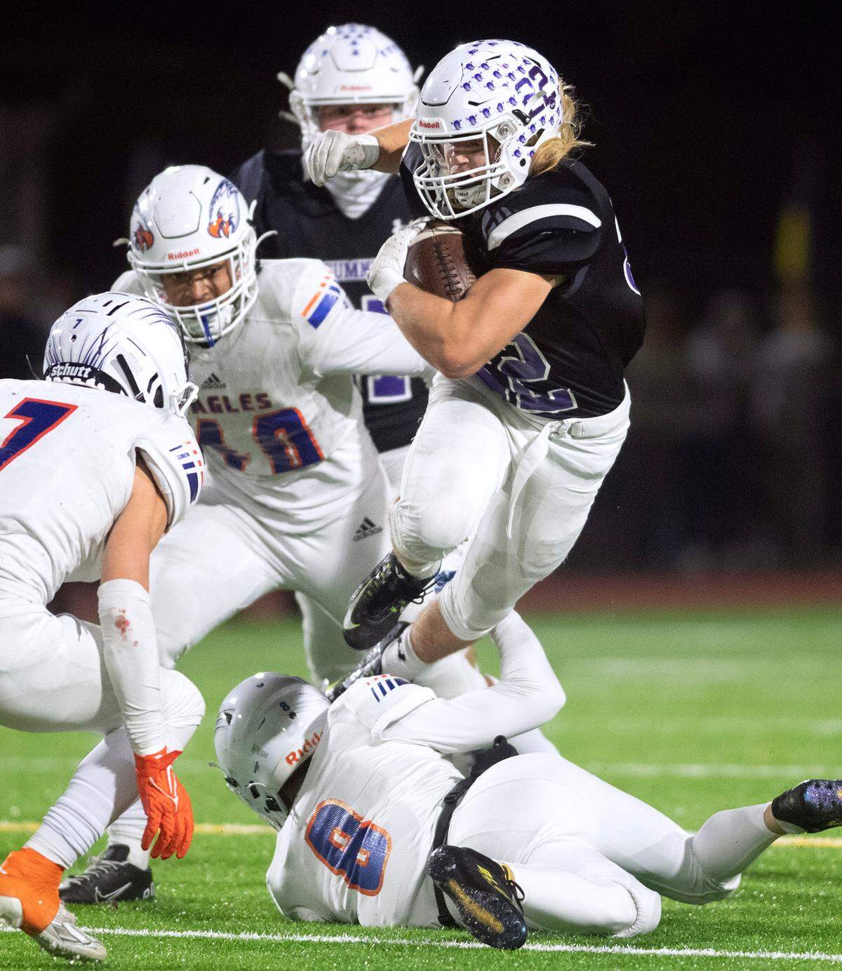 Sumner running back Matthew Spurbeck tries to leap past Graham-Kapowsin defenders Garrett Ott (7), Jabez Woods and Ethan Pletcher during Friday night’s 4A football state quarterfinal game at Sunset Chev Stadium in Sumner, Washington, Nov. 18, 2022. Graham-Kapowsin won the game, 28-21.