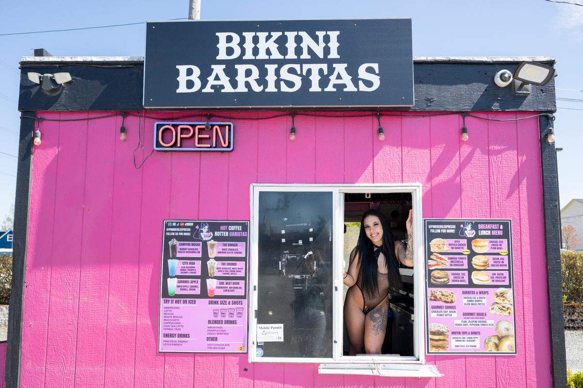 Barista Jayla Mason leans against the window of bikini barista stand Pink Sugar Espresso for a portrait on Wednesday, April 16, 2025, in Tacoma, Wash.