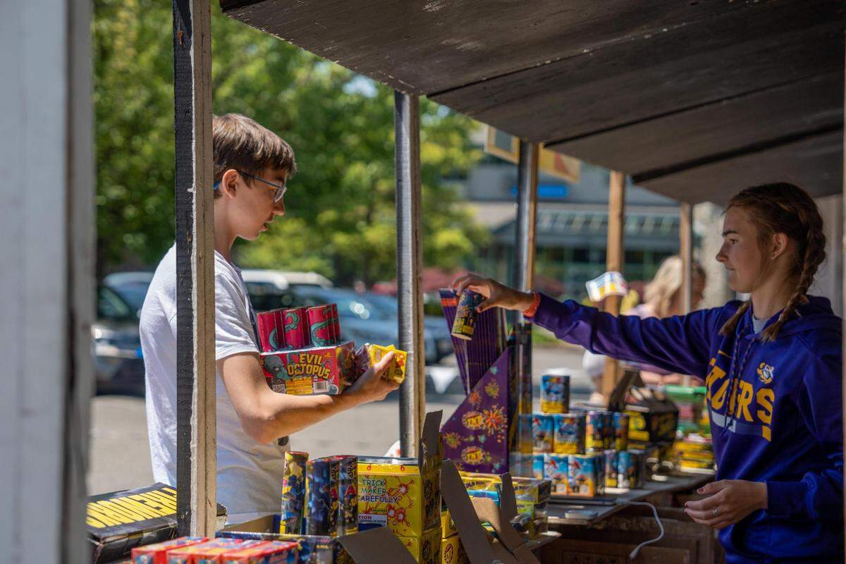 Hannah Carroll hands Lucas Hearlson his fireworks that he purchased for the Fourth of July at one of the many fireworks stands in Gig Harbor. The stand at 5010 Point Fosdick Dr. NW is run by Carrol and David Whitehurst. Carrol’s dad has been working for TNT Fireworks for 28 years and she has been running stands for the past six years. The pop-up shop will be affected by the fireworks ban that takes effect in the city next year.