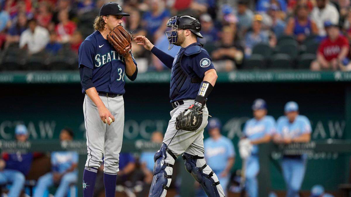 Seattle Mariners catcher Curt Casali, right, heads to the mound to settle starting pitcher Logan Gilbert (36) after they gave up two runs to the Texas Rangers during the fourth inning of a baseball game in Arlington, Texas, Sunday, Aug. 14, 2022. (AP Photo/LM Otero)