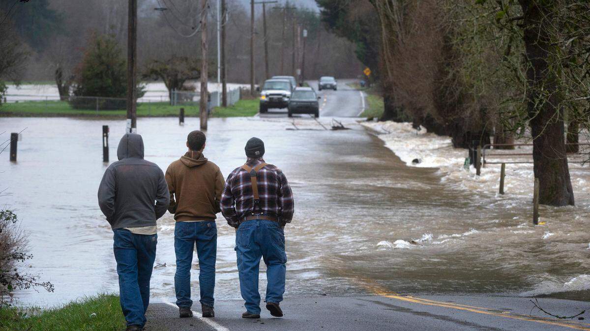 Spectators take in the view of Chehalis River floodwaters shutting down Independence Road south of Rochester, Washington, on Friday, Jan. 7, 2022.