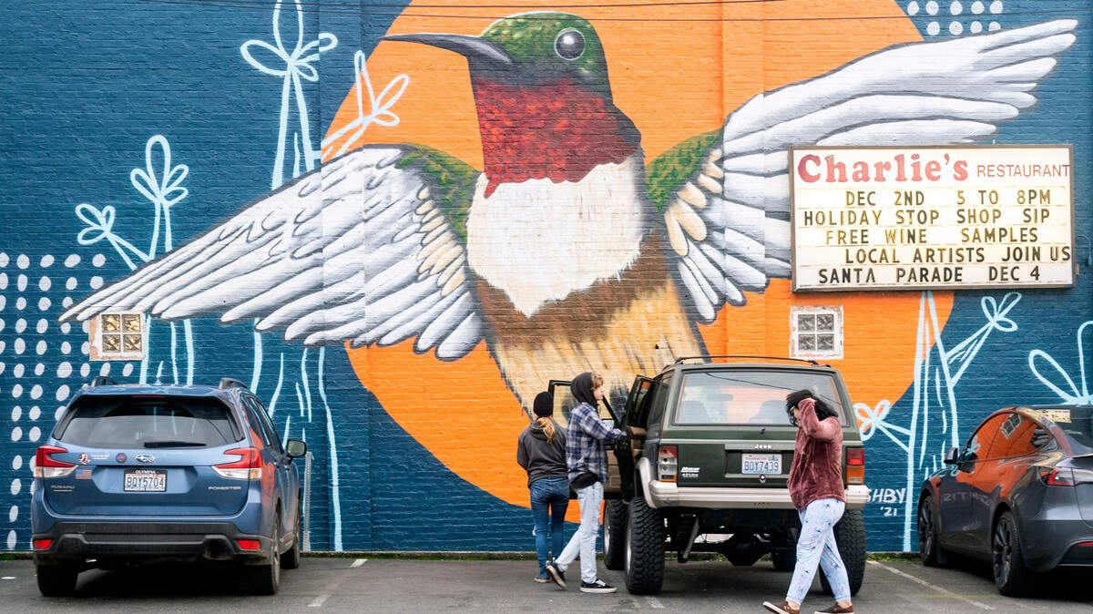 People get out their vehicle in front of a mural that was recently finished on west-facing side of Charlie’s Restaurant on the 100 block of West Main Street in downtown Puyallup on Thursday afternoon. The Puyallup Main Street Association commissioned artist Curtis Ashby to paint the large bird mural.