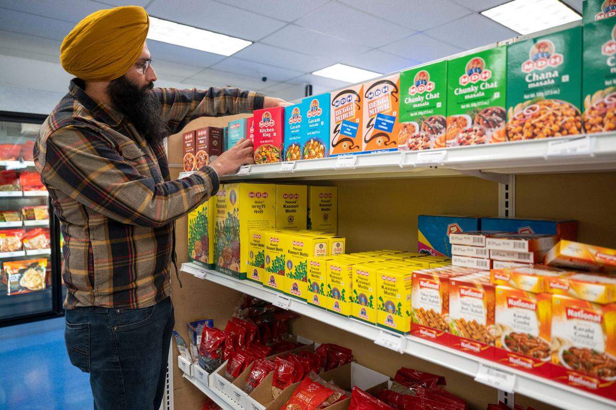 Ravinder Singh organizes shelves at his store, Spice World at 10417 Canyon Rd., on Saturday, Feb. 25, 2023. After moving to Puyallup, he sensed a need for a well-stocked Indian grocery in Pierce County.
