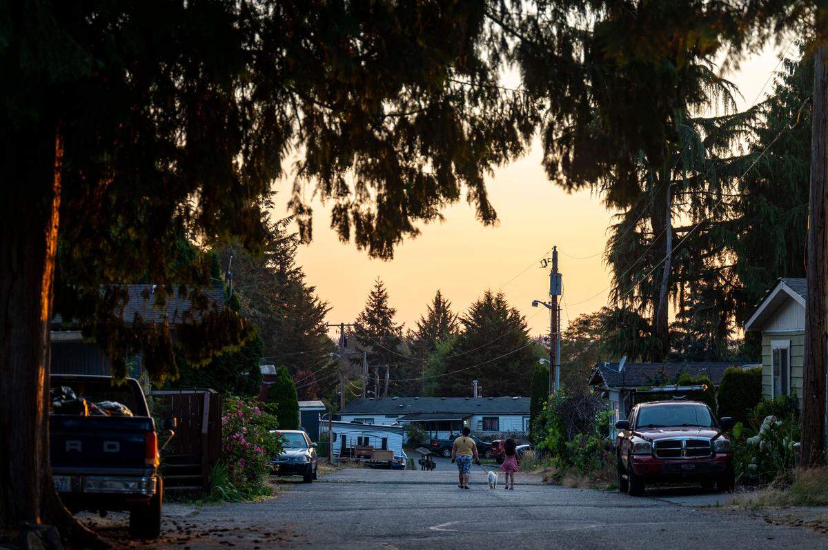A mother and daughter walk their dog at sunset through Meridian Estates on Wednesday, July 27, 2022, in Puyallup, Wash.