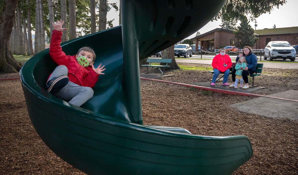 Zane LaBarge, 4, plays on the slide at Central Park in Orting, Washington, on Wednesday, Feb. 8, 2023. Zane is the son of Angela LaBarge (back left) of Bonney Lake. They were visiting with friend Maureen Larson of Puyallup and her daughter, Maven, 3.