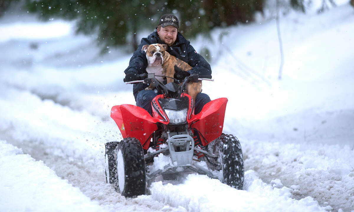 Marty Rodgers is accompanied by his dog, Ozzy, as they knock down snow ruts in their Tumwater, Washington, neighborhood on Friday, Feb. 13, 2021. Rodgers had spent the morning pulling free motorists stuck in the snow, including an ambulance.