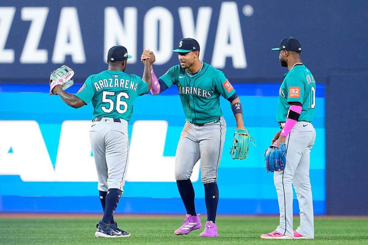 TORONTO, ONTARIO - OCTOBER 12: Randy Arozarena #56, Julio Rodriguez #44 and Victor Robles #10 of the Seattle Mariners celebrate on the field after defeating the Toronto Blue Jays in game one of the American League Championship Series at Rogers Centre on October 12, 2025 in Toronto, Ontario. (Photo by Mark Blinch/Getty Images)