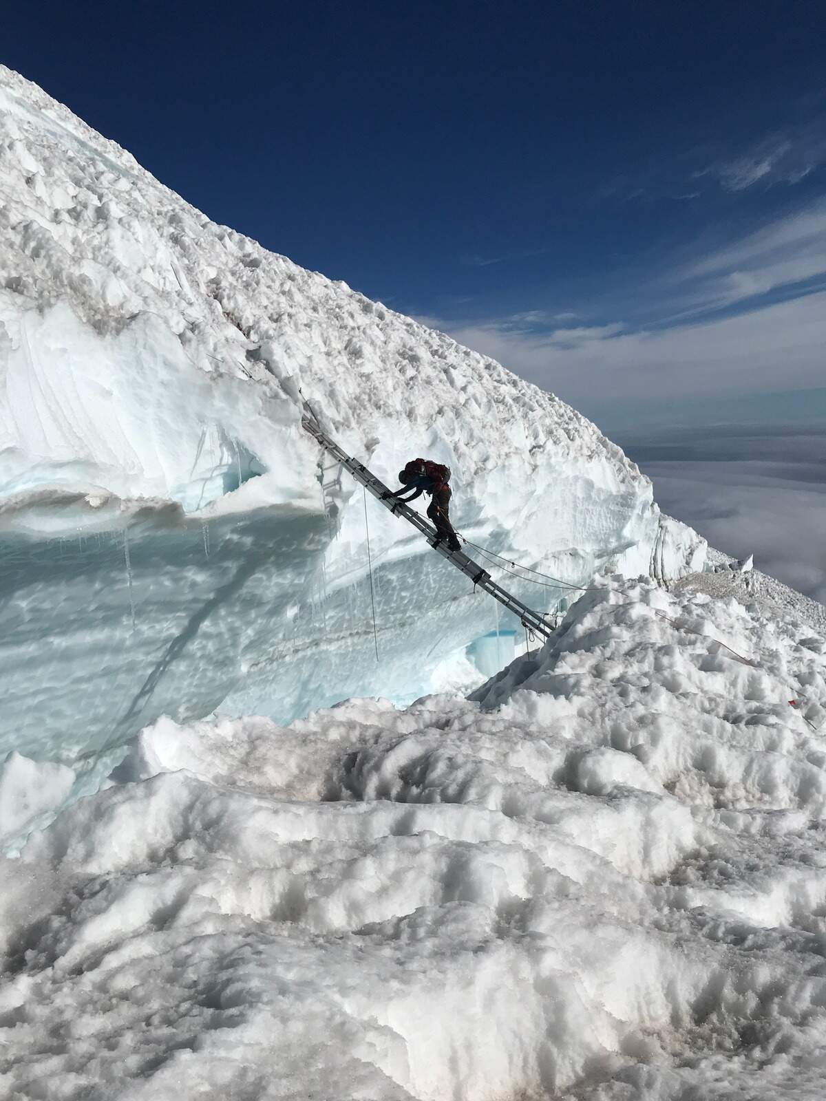 A climber making his way across a ladder “adjunct” on Mount Rainier’s Ingraham Direct Route.