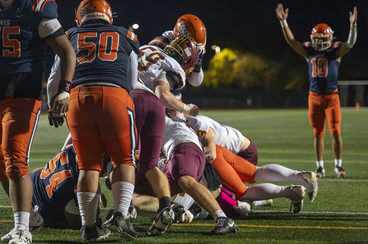 Lakes quarterback Jadis Lefono (10) raises his arms as Lakes running back Toetu Moliga-Taiepisi (22) lands in the end zone under a pile of Capital defenders for a touchdown on Friday, Oct. 24, 2025, in Lakewood, Wash.
