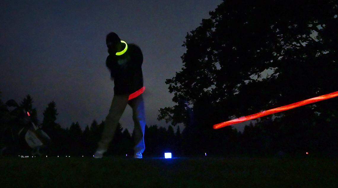 A golfer drives through the dark during a Glow Golf nighttime play preview session on the Williams Nine course at Meadow Park Golf Course in Tacoma, Washington, on Tuesday, Sept. 19, 2023.