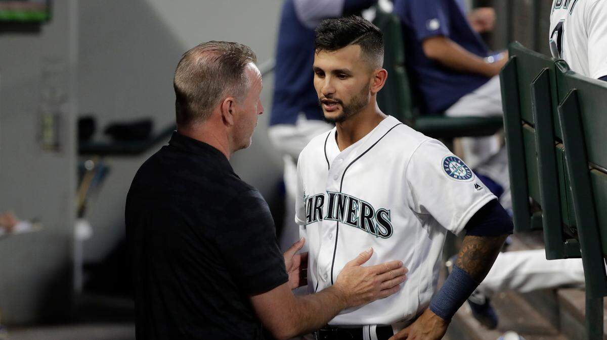Seattle Mariners trainer Rob Nodine, left, talks with second baseman Tim Lopes in the dugout during the sixth inning of a baseball game against the Detroit Tigers, Thursday, July 25, 2019, in Seattle. Lopes, who was hit by a pitch during the fourth inning, but stayed in the game, was replaced in the seventh inning by Dylan Moore. (AP Photo/Ted S. Warren)