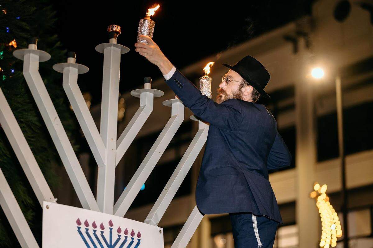 Rabbi Mendel Kesselman, director of Chabad of Pierce County, lights the menorah on Thursday, Dec. 26, 2024 in front of the Pantages Theater in downtown Tacoma.