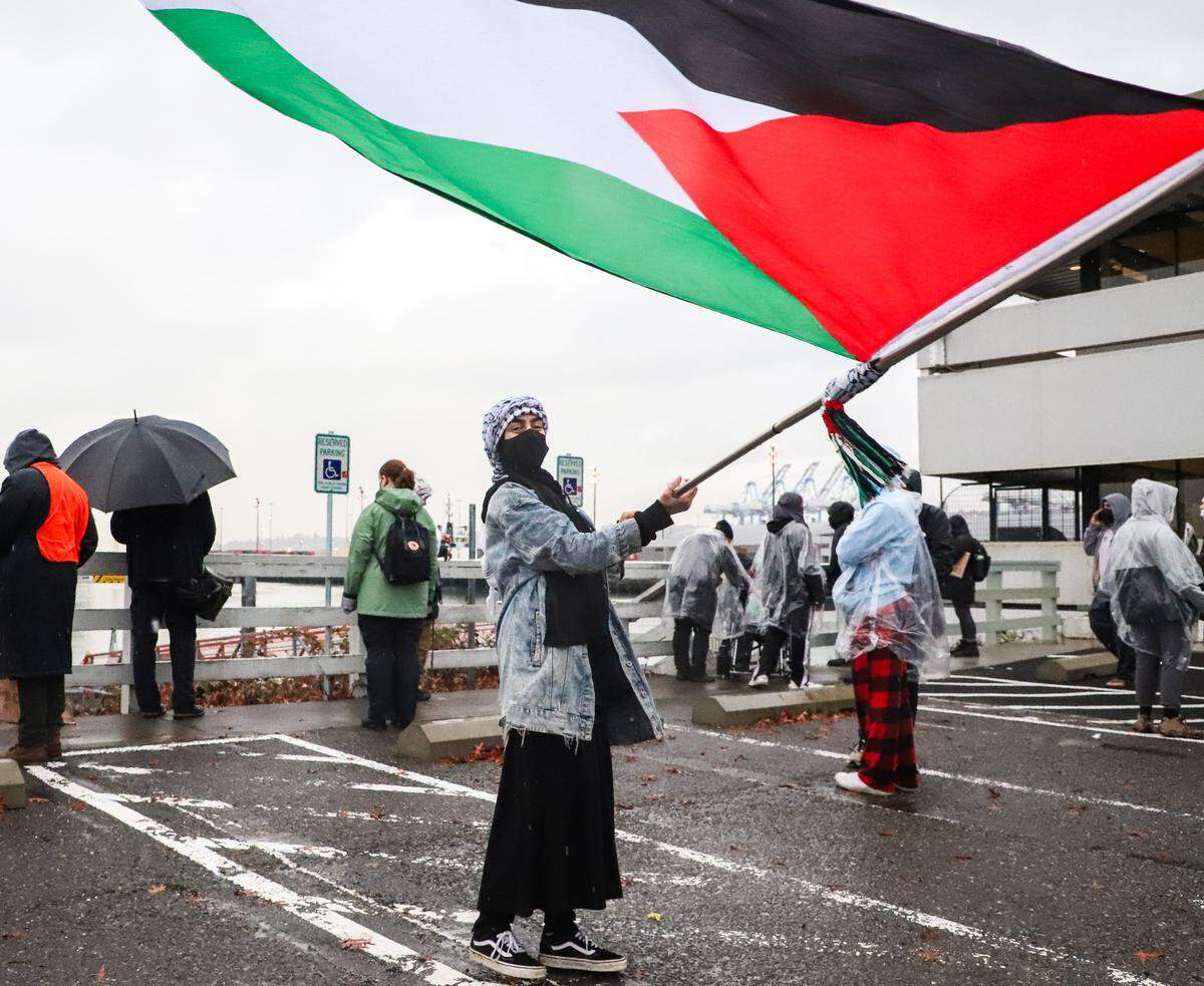 Nour, a Palestinian- American, waves the Palestinian flag on a pier at the Port of Tacoma during a protest that was mean to block a ship that protesters thought was going to deliver weapons and equipment to Israel, on Monday, November 6, 2023.