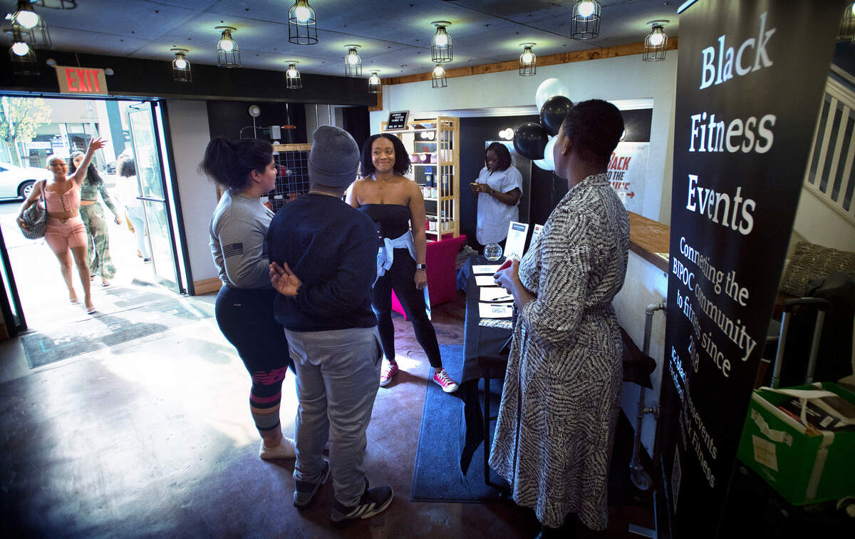 Nicolette Slaughter (center) and Jasmine Bryson (right) talk with guests about their Black Fitness Events non-profit organization as others arrive for the Black Night Market event at Edison Square in Tacoma, Washington, on Friday, April 29, 2022.