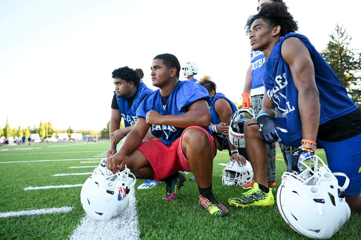 Student-athletes watch as another squad runs plays during a football practice at Graham-Kapowsin High School, Wednesday, Aug. 16, 2023, in Graham, Wash.