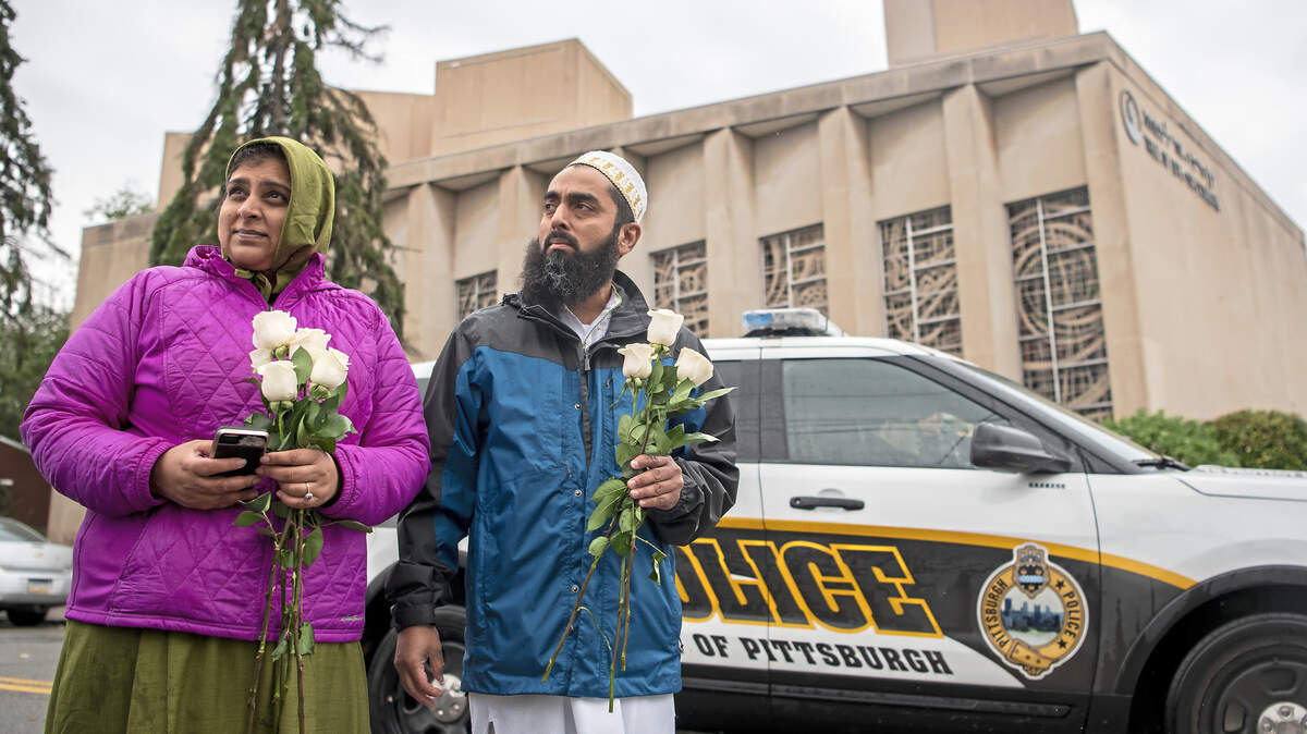 Samina Mohamedali, left, and her husband Kutub Ganiwalla, members of the Dawoodi Bohra Muslim community, prepare to place flowers on a memorial in front of the Tree of Life Congregation.