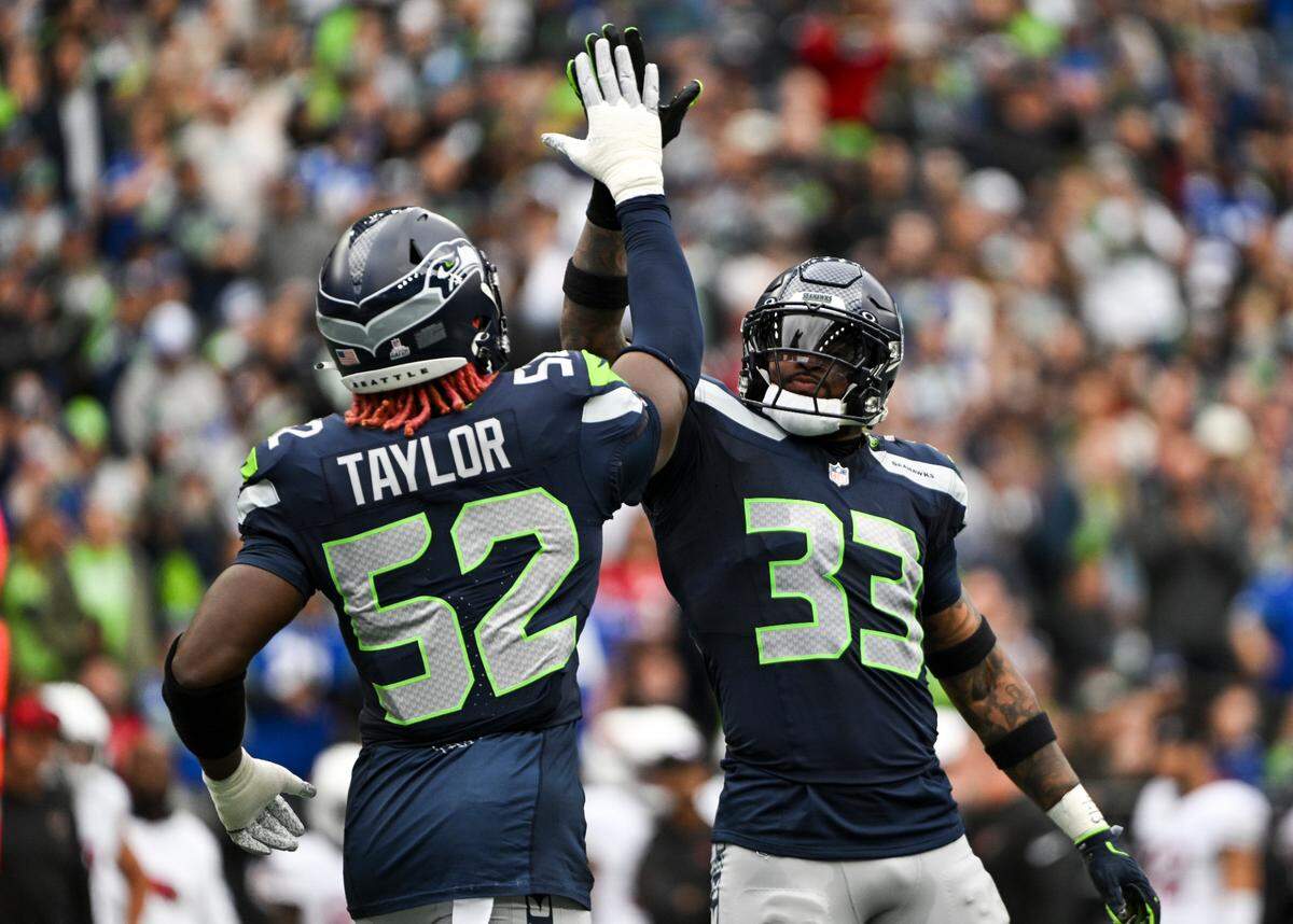 Seattle Seahawks linebacker Darrell Taylor (52) and safety Jamal Adams (33) celebrate a play against the Arizona Cardinals during the first quarter of the game at Lumen Field, Sunday, Oct. 22, 2023, in Seattle, Wash.