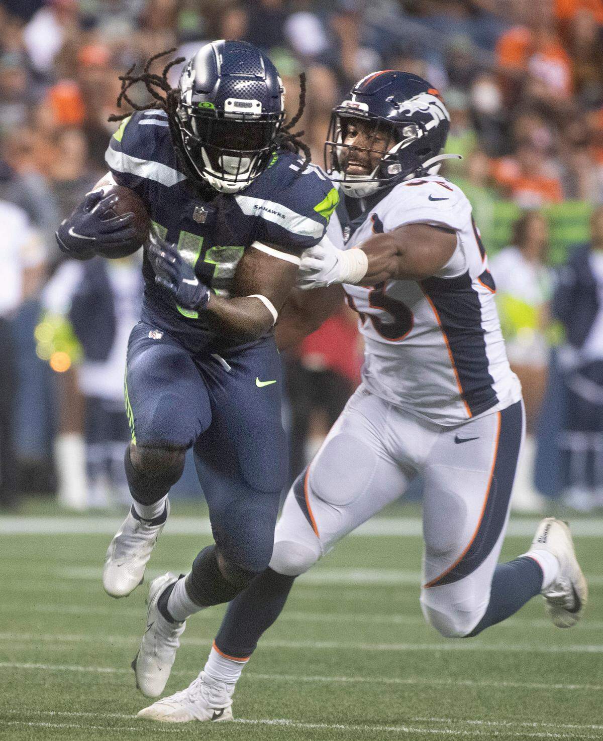 Seahawks running back Alex Collins breaks away from Broncos linebacker Jonathon Cooper during Saturday night’s NFL preseason football game at Lumen Field in Seattle, Washington, on Saturday, Aug. 21, 2021.