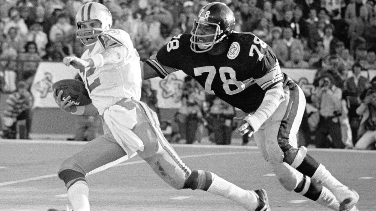 File-This Jan. 18, 1976, file photo shows Pittsburgh Steeler Dwight White (78), chasing down Dallas Cowboys quarterback Roger Staubach in the second quarter of Super Bowl X in Miami. Members of a special panel of 26 selected all of them for the position as part of the NFL’s celebration of its 100th season. All won league titles except Marino. All are in the Hall of Fame except Brady and Manning, who are not yet eligible. On Friday night, quarterback was the final position revealed for the All-Time Team. (AP Photo/File)