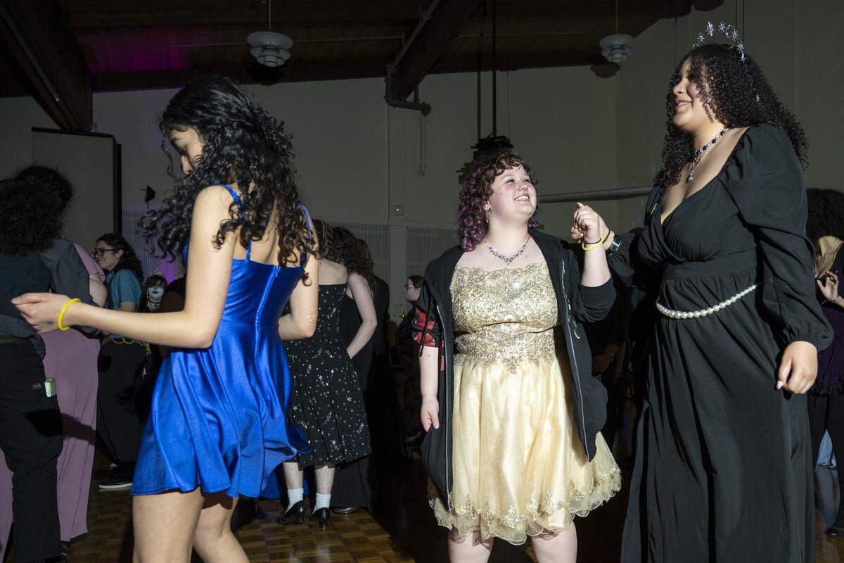 Friends Evelynn Galler, center, and Lei'Lene Ortega, right, take to the dance floor with their friend group at Queer Prom on Saturday, April 18, 2026, in Tacoma, Wash. The prom was put on by the Oasis Youth Center and held at Pacific Lutheran University.