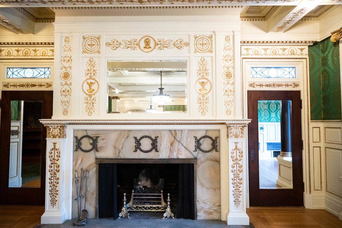 A view of a fireplace covered in gold-painted adornments in the great room in the original Rust Mansion.