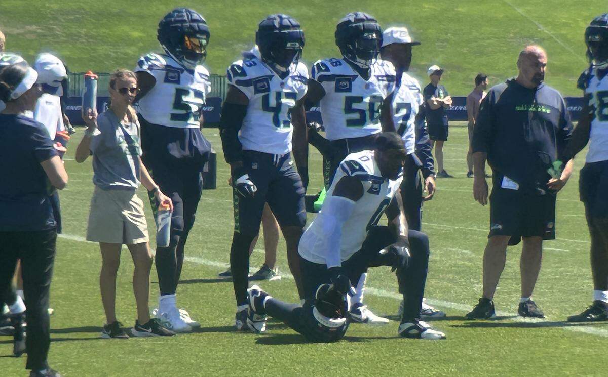 DeMarcus Lawrence (0, kneeling) watches over his fellow defensive linemen and linebackers drilling in the sixth practice of Seattle Seahawks NFL training camp Tuesday, July 29, 2025, at the Virginia Mason Athletic Center in Renton.