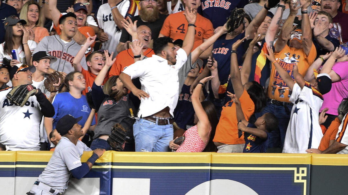 Seattle Mariners right fielder Mallex Smith, left, jumps up the right field wall as fans attempt to catch a home run by Houston Astros’ Carlos Correa during the fifth inning of a baseball game Friday, Aug. 2, 2019, in Houston.
