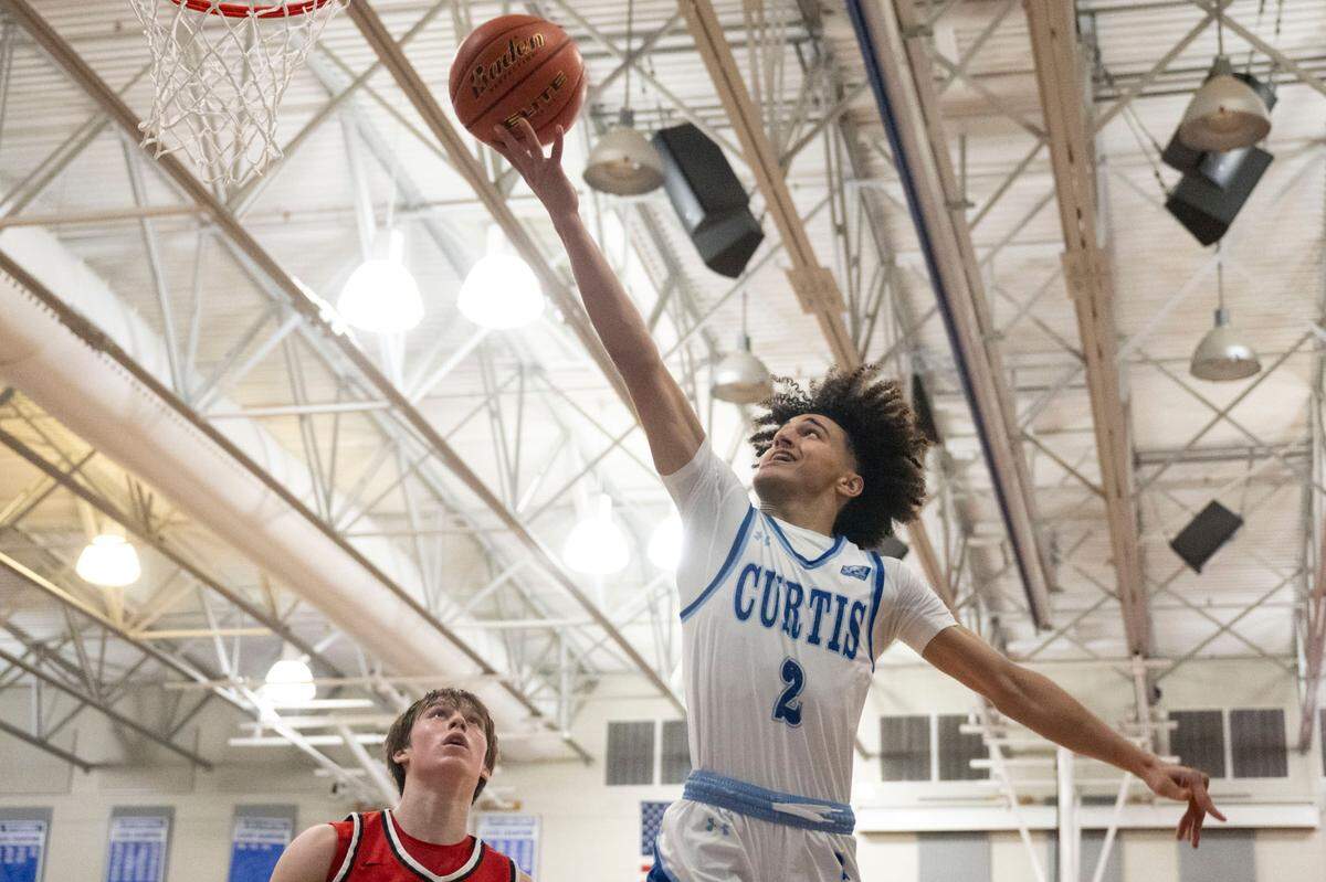 Curtis guard Bilal El Ghalemi (2) goes in for a layup as Camas guard Theo McMillan (20) looks on during the second quarter of a District 3/4 semifinal game on Thursday, Feb. 16, 2023, at Curtis High School in University Place, Wash.