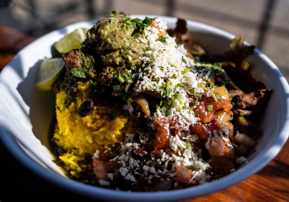 Chef Nicole de la Paz features a Cantina Bowl with chimichurri steak served over yellow rice with peppers, onions, Cuban black beans, guacamole and pico de gallo at her restaurant The Church Cantina on South Tacoma Way on Thursday, March 10, 2022.