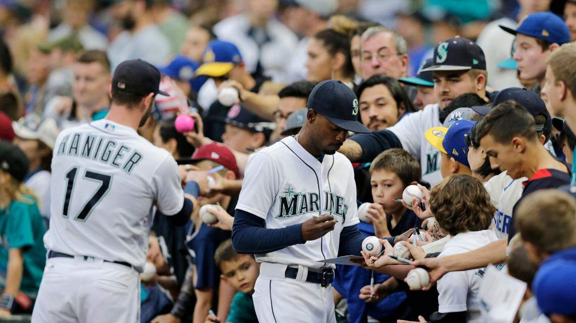 Seattle Mariners’ Dee Gordon, right, and Mitch Haniger sign autographs before a baseball game against the Texas Rangers, Saturday, Sept. 29, 2018, in Seattle. (AP Photo/John Froschauer)
