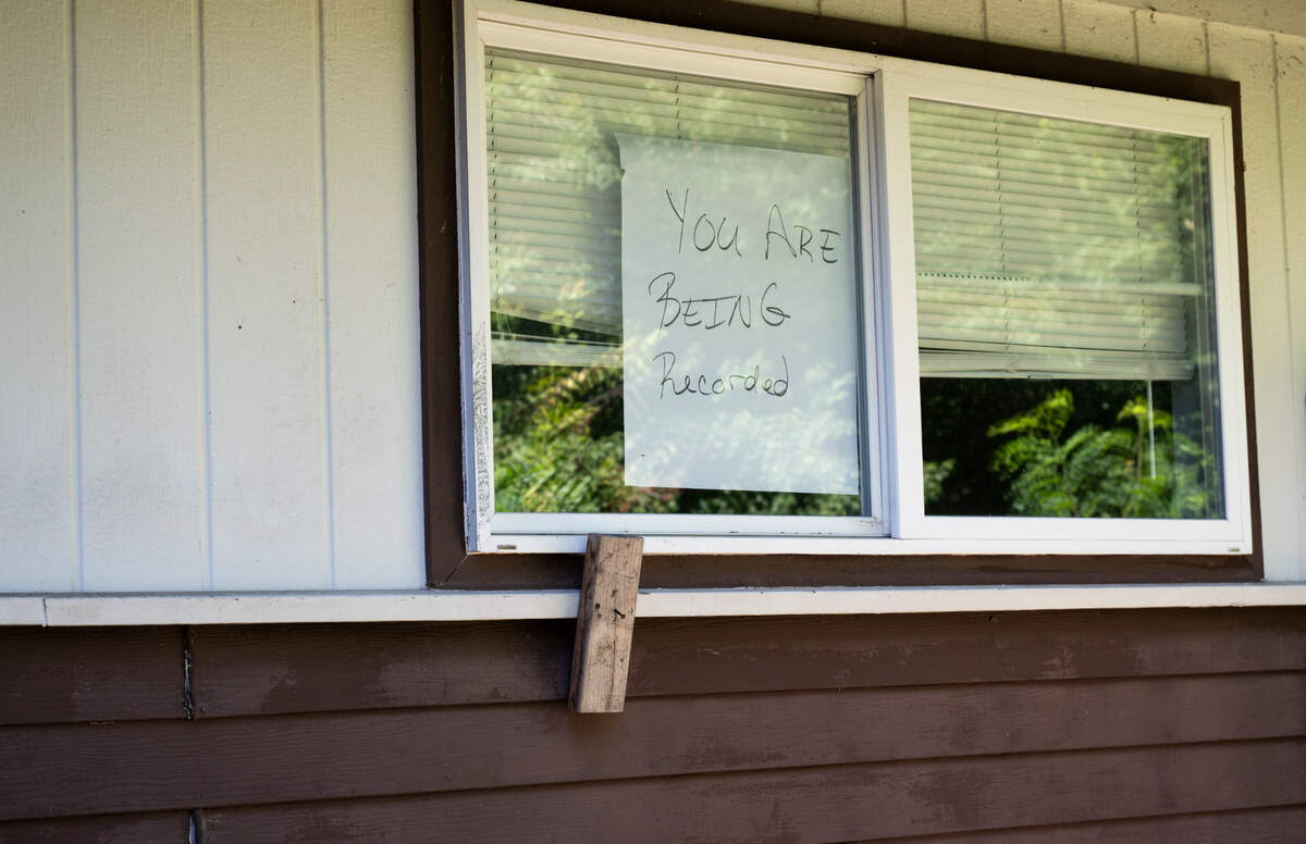A sign advising of recording hangs in Betty Halbert’s window after she said a person broke into her backyard and peered into her bedroom.